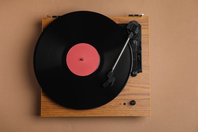 Photo of Modern vinyl record player with disc on brown background, top view