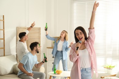 Photo of Young woman singing karaoke with friends at home