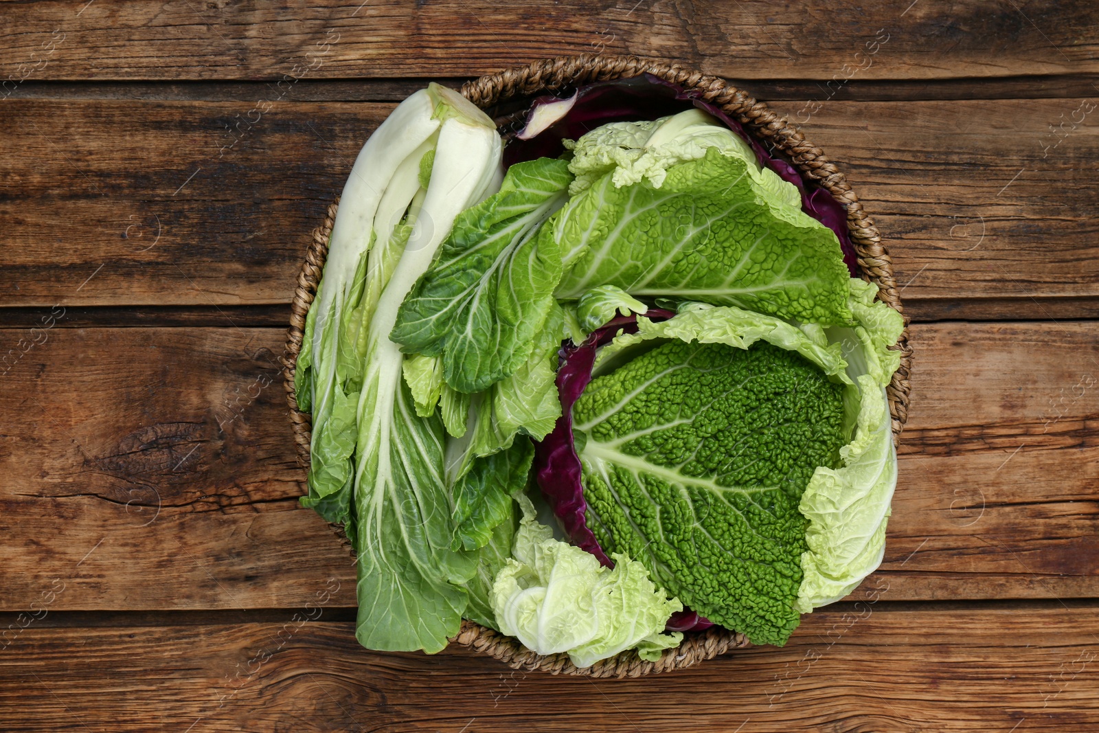 Photo of Many different cabbage leaves on wooden table, top view