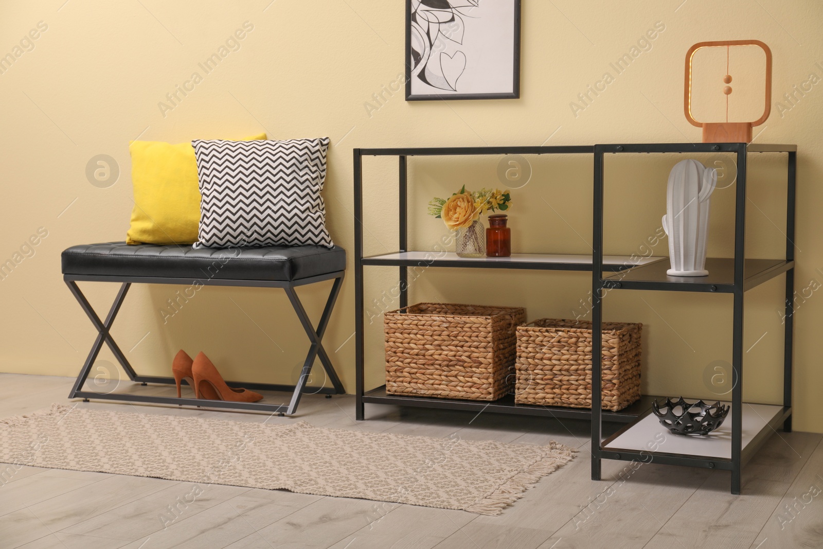 Photo of Console table with decor and bench near beige wall in hallway. Interior design