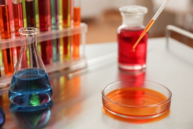 Photo of Dripping color liquid into Petri dish on table. Solution chemistry