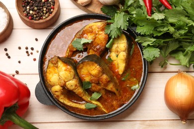 Photo of Tasty fish curry and ingredients on white wooden table, flat lay. Indian cuisine