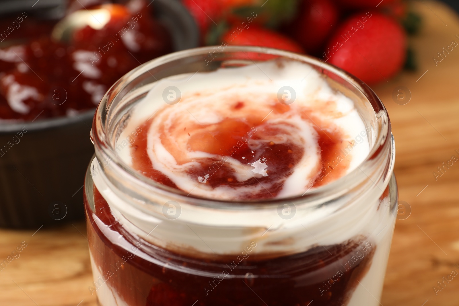 Photo of Tasty yoghurt with jam and strawberries on wooden board, closeup