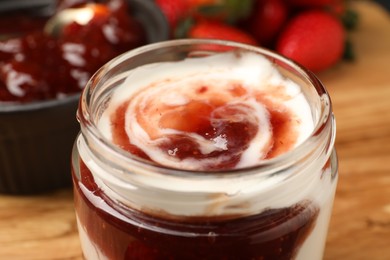 Photo of Tasty yoghurt with jam and strawberries on wooden board, closeup