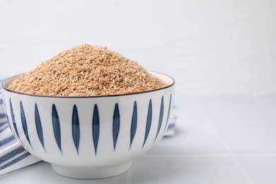 Photo of Dry wheat groats in bowl on white table, closeup. Space for text