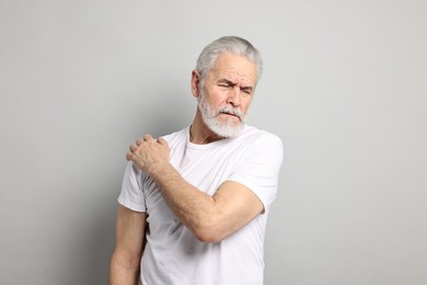 Photo of Arthritis symptoms. Man suffering from pain in shoulder on gray background