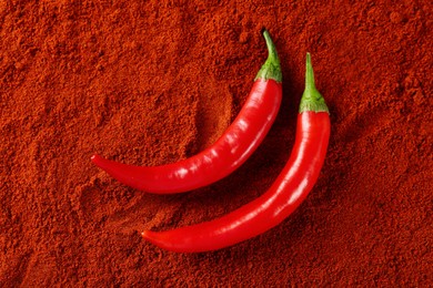 Photo of Fresh chili peppers on paprika powder, flat lay