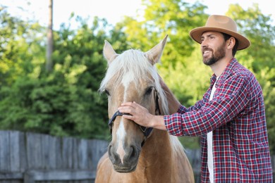 Photo of Handsome man with adorable horse outdoors. Lovely domesticated pet