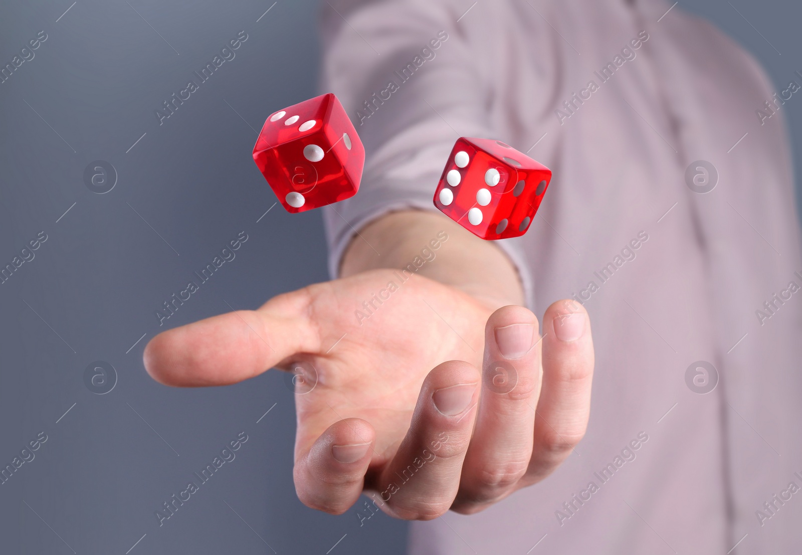 Image of Man throwing red dice on grey background, closeup