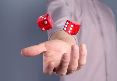 Image of Man throwing red dice on grey background, closeup