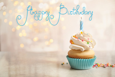 Image of Delicious cupcake with candle on light table against blurred lights. Happy Birthday