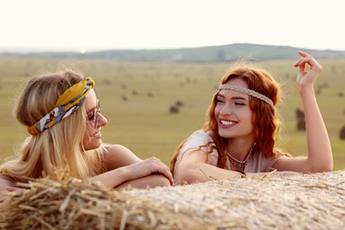 Photo of Beautiful hippie women near hay bale in field