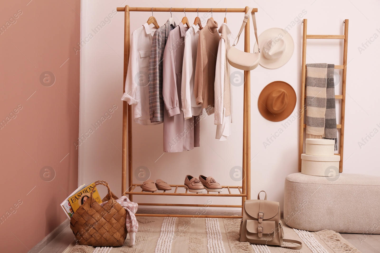 Photo of Rack with different stylish clothes and shoes near white wall in room