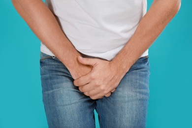 Photo of Man suffering from pain on turquoise background, closeup. Urology problems