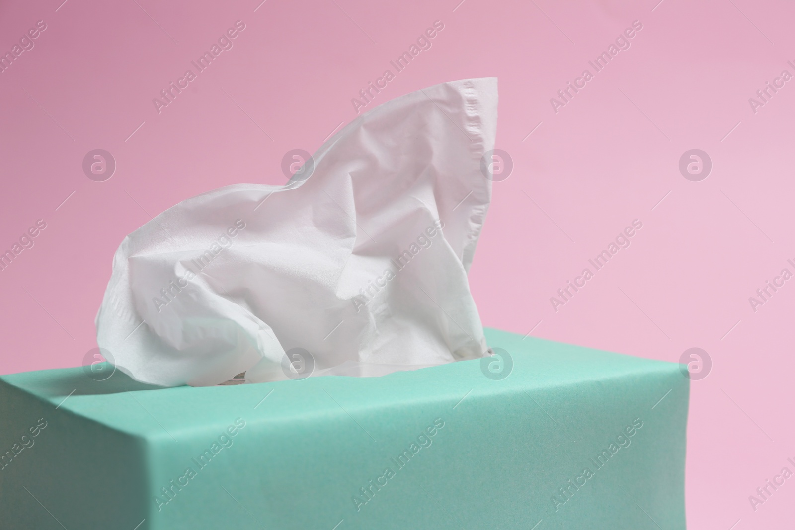 Photo of Box with paper tissues on pink background, closeup