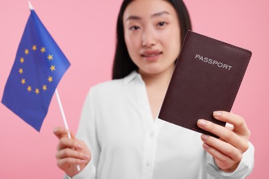 Photo of Immigration to European Union. Woman with passport and flag on pink background, selective focus