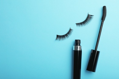 Photo of Flat lay composition of black mascara and false eyelashes on color background, space for text
