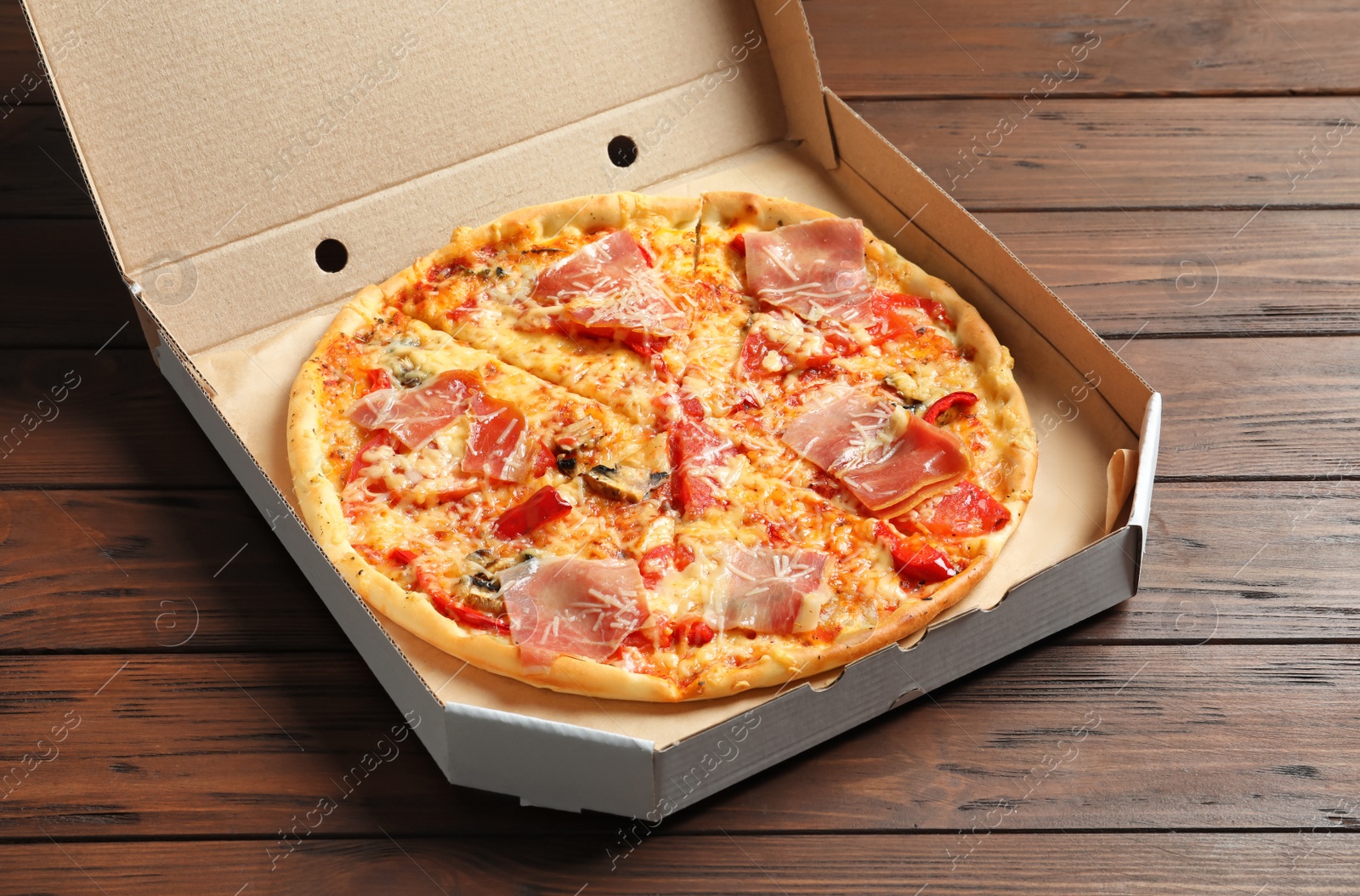 Photo of Carton box with delicious pizza on wooden background