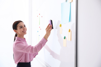 Young teacher cleaning whiteboard in modern classroom