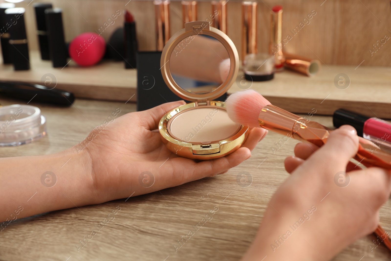 Photo of Woman applying makeup at dressing table, closeup