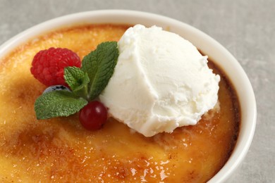 Delicious creme brulee with scoop of ice cream, fresh berries and mint on light grey background, closeup