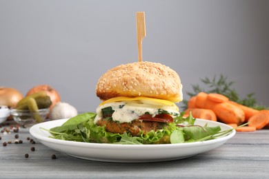 Photo of Delicious vegetarian burger served on grey wooden table