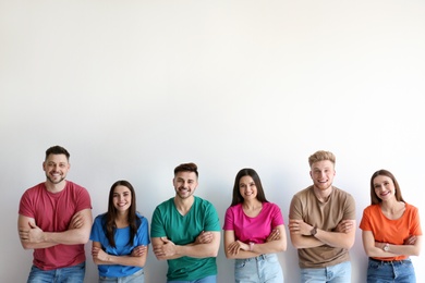 Group of happy people posing near light wall, space for text