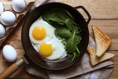 Photo of Delicious fried egg with spinach served on wooden table, flat lay
