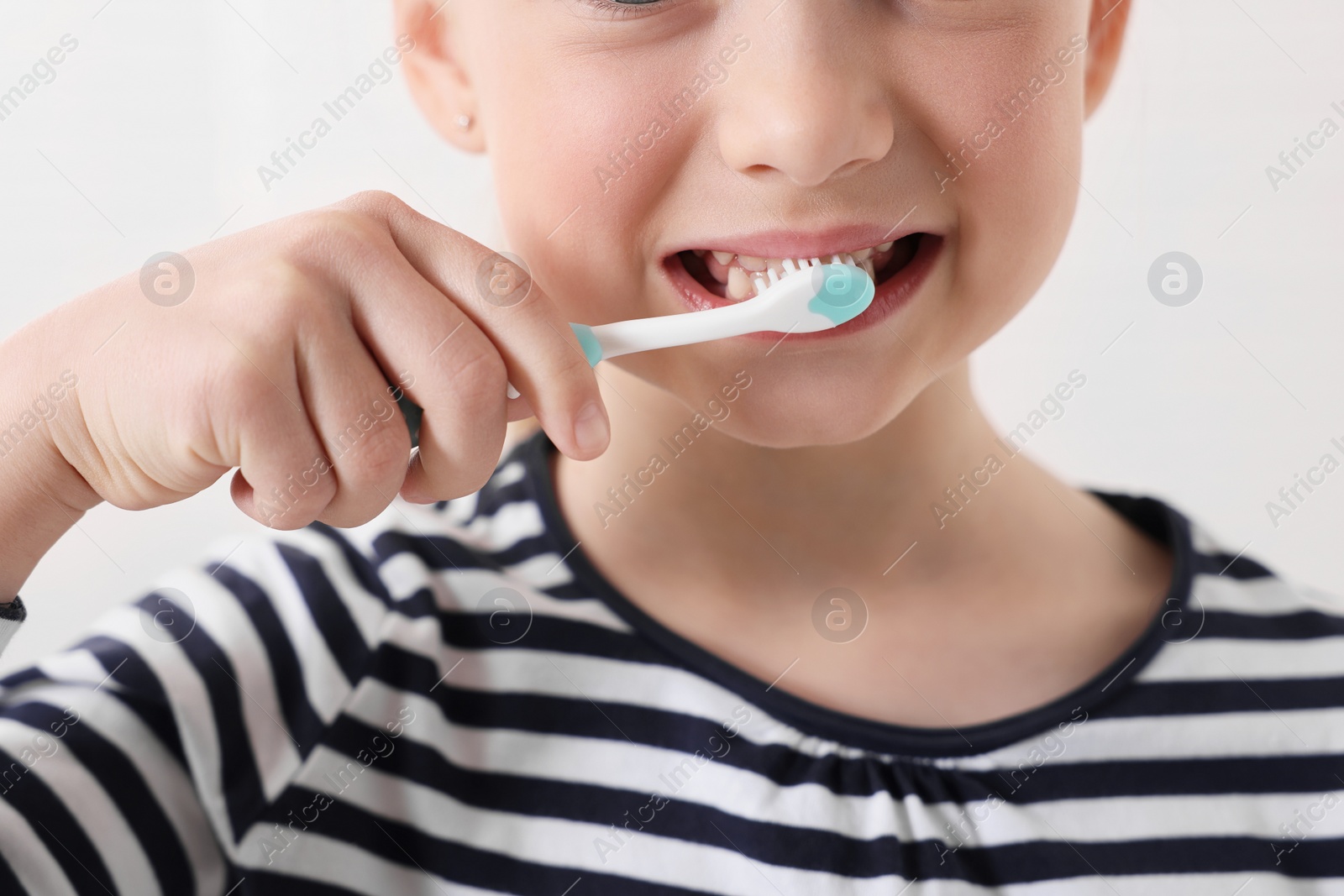 Photo of Little girl brushing her teeth with plastic toothbrush on white background, closeup