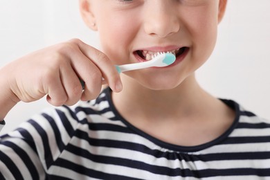 Photo of Little girl brushing her teeth with plastic toothbrush on white background, closeup