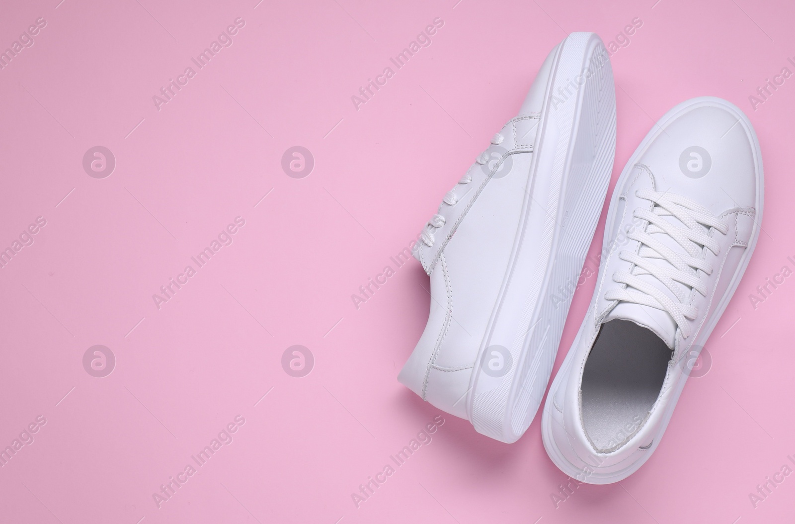 Photo of Pair of stylish white sneakers on pink background, top view. Space for text