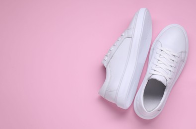 Photo of Pair of stylish white sneakers on pink background, top view. Space for text