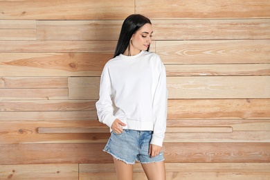 Photo of Portrait of young woman in sweater at wooden wall. Mock up for design