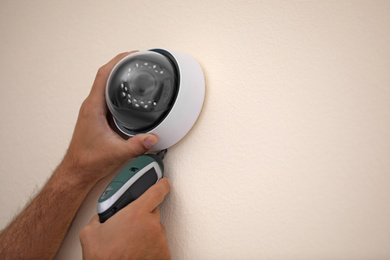 Photo of Technician installing CCTV camera on wall, closeup. Space for text