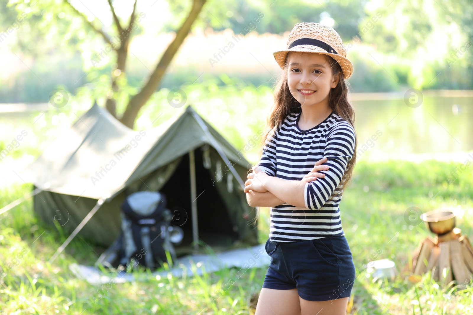 Photo of Little girl near tent outdoors. Summer camp