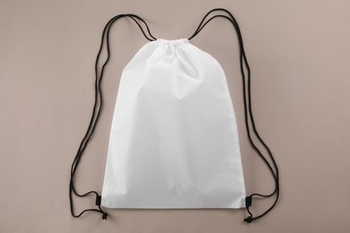 Photo of One white drawstring bag on beige background, top view