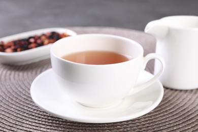 Photo of Aromatic tea in cup and saucer on table, closeup