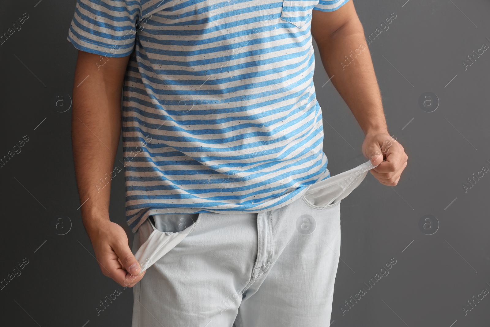 Photo of Man showing empty pockets on grey background, closeup