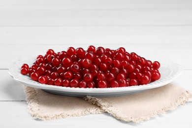 Photo of Plate with ripe red currants on white wooden table