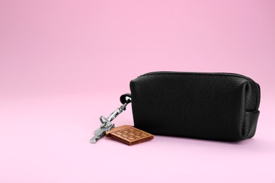 Photo of Leather case with key on pink background. Space for text