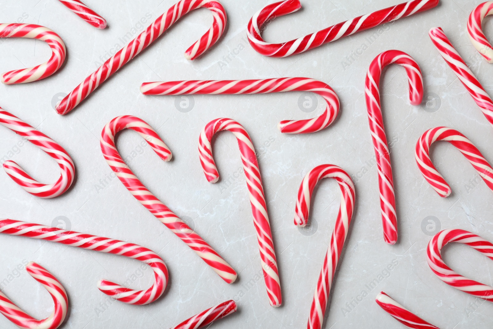 Photo of Sweet Christmas candy canes on grey background, flat lay