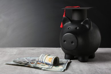 Photo of Scholarship concept. Piggy bank, graduation cap and banknotes on grey table