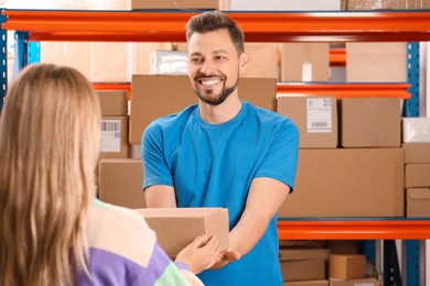 Photo of Worker giving parcel to woman at post office, space for text