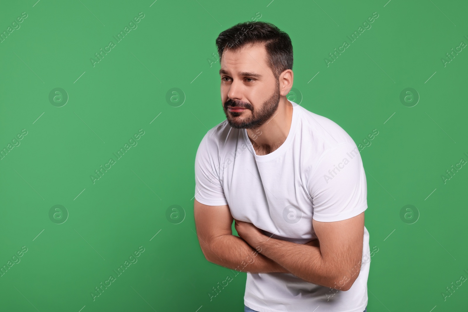 Photo of Man suffering from stomach pain on green background, space for text