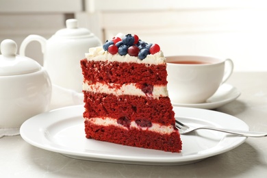 Photo of Plate with piece of delicious homemade red velvet cake on table