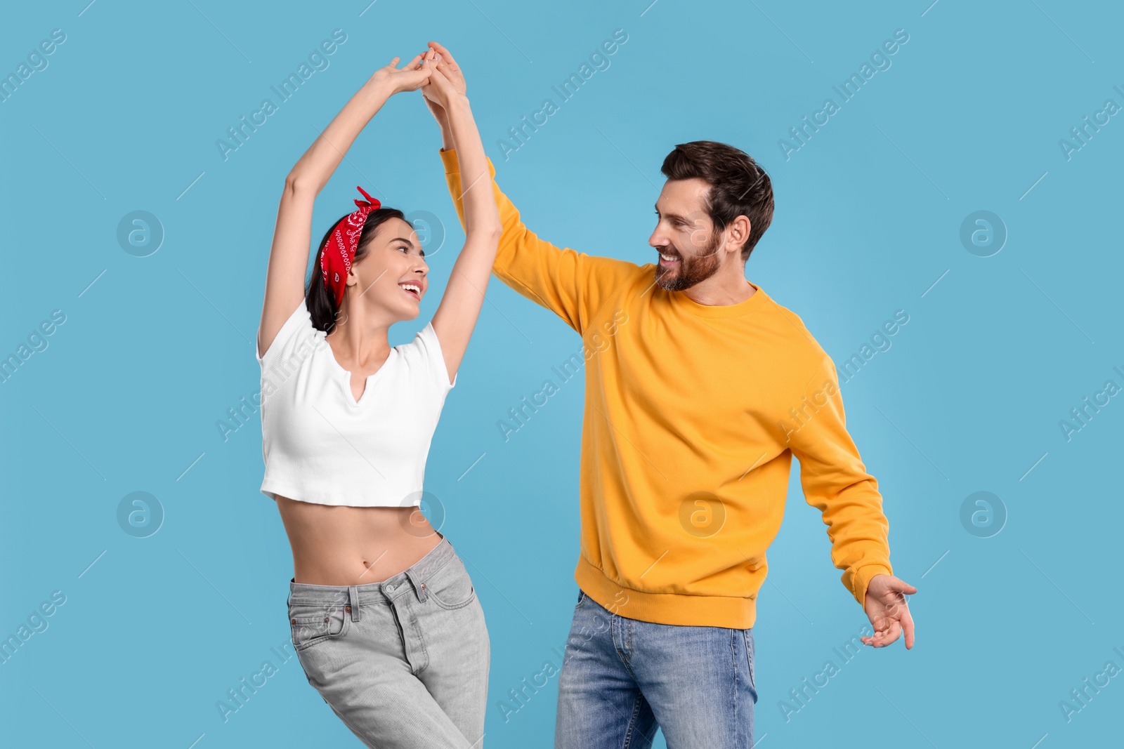 Photo of Happy couple dancing together on light blue background