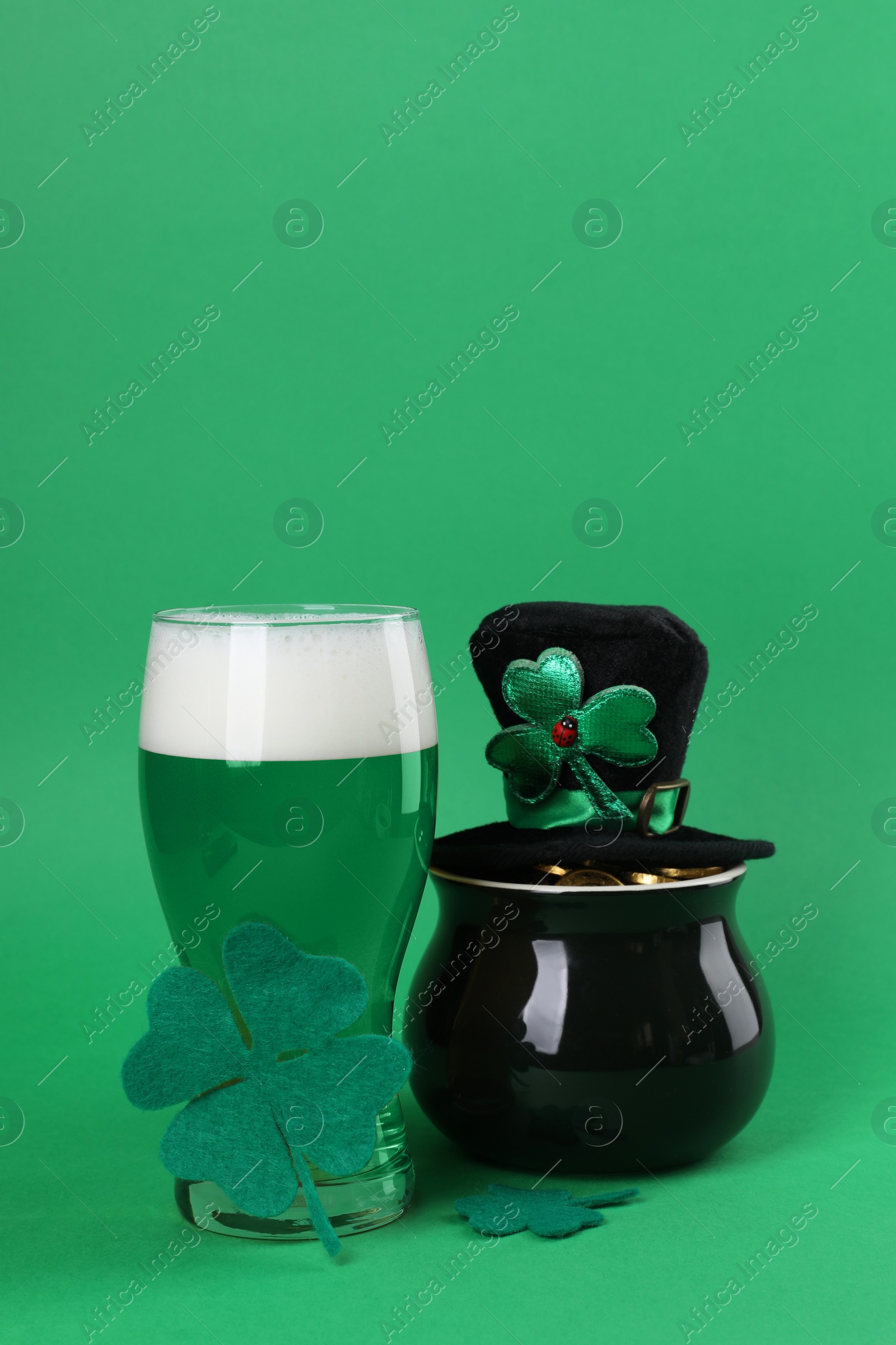 Photo of St. Patrick's day party. Green beer, leprechaun hat, pot of gold and decorative clover leaves on green background