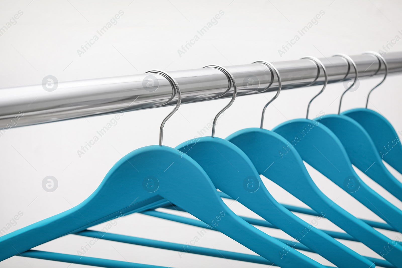 Photo of Clothes hangers on metal rail against light background