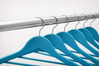 Photo of Clothes hangers on metal rail against light background