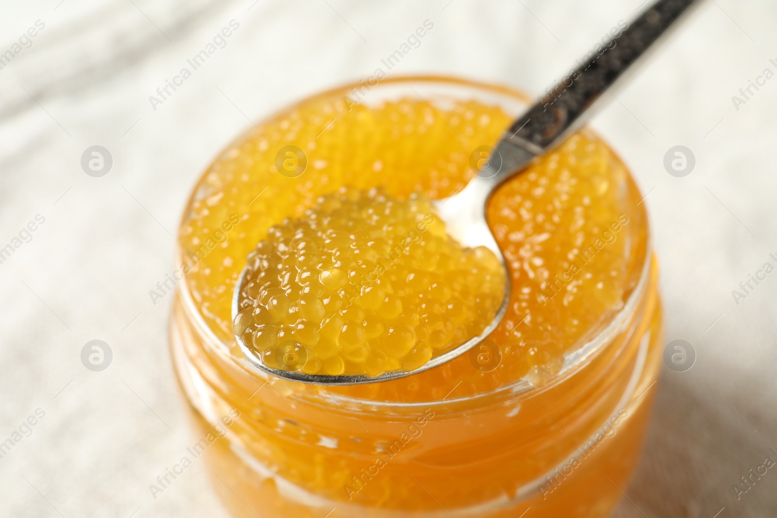 Photo of Fresh pike caviar in glass jar and spoon on table, closeup